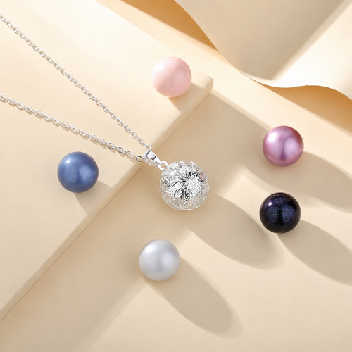 Collier bola Alba argenté posé sur fond crème, entouré de perles décoratives