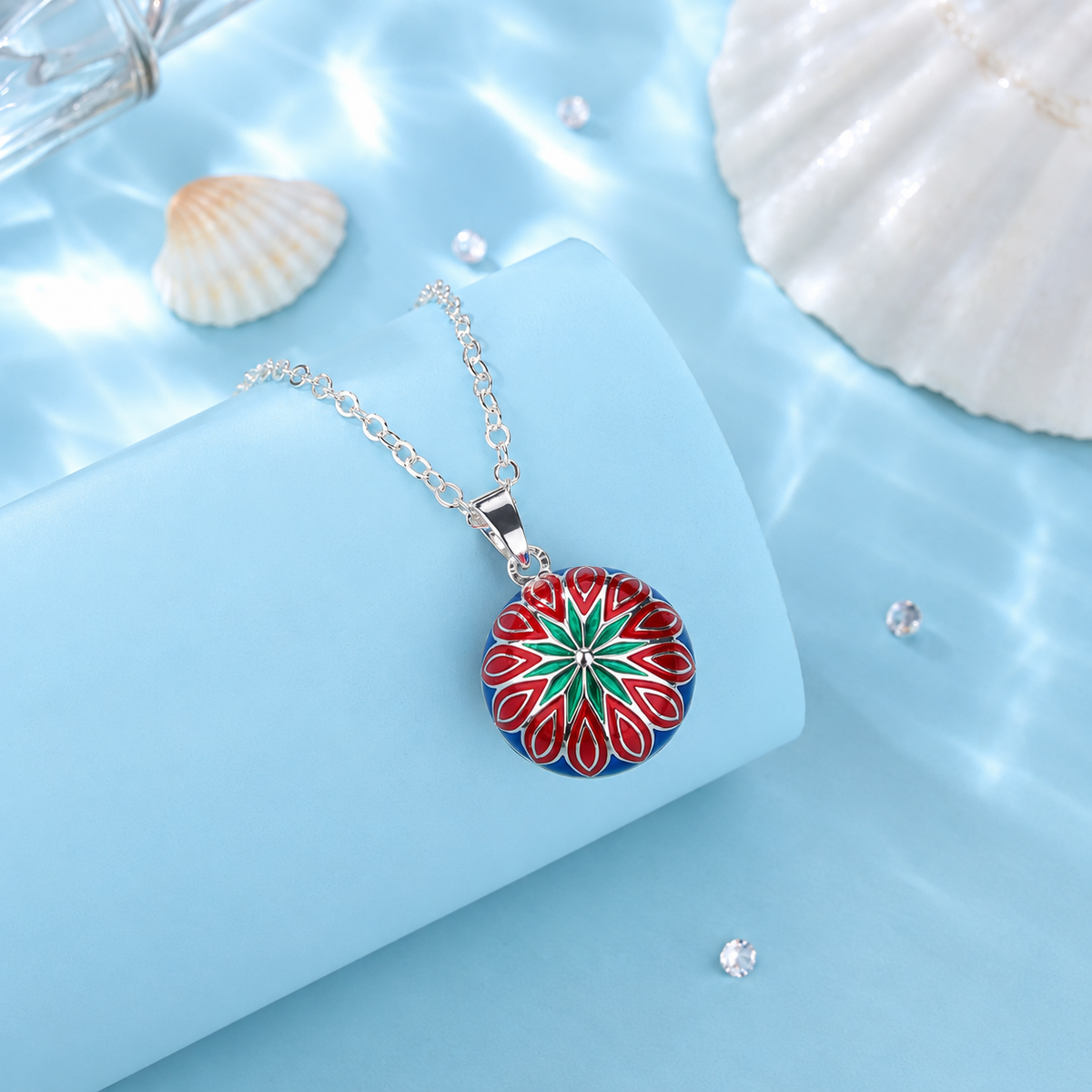 Collier bola Aria coloré posé sur un support bleu, coquillages en décor
