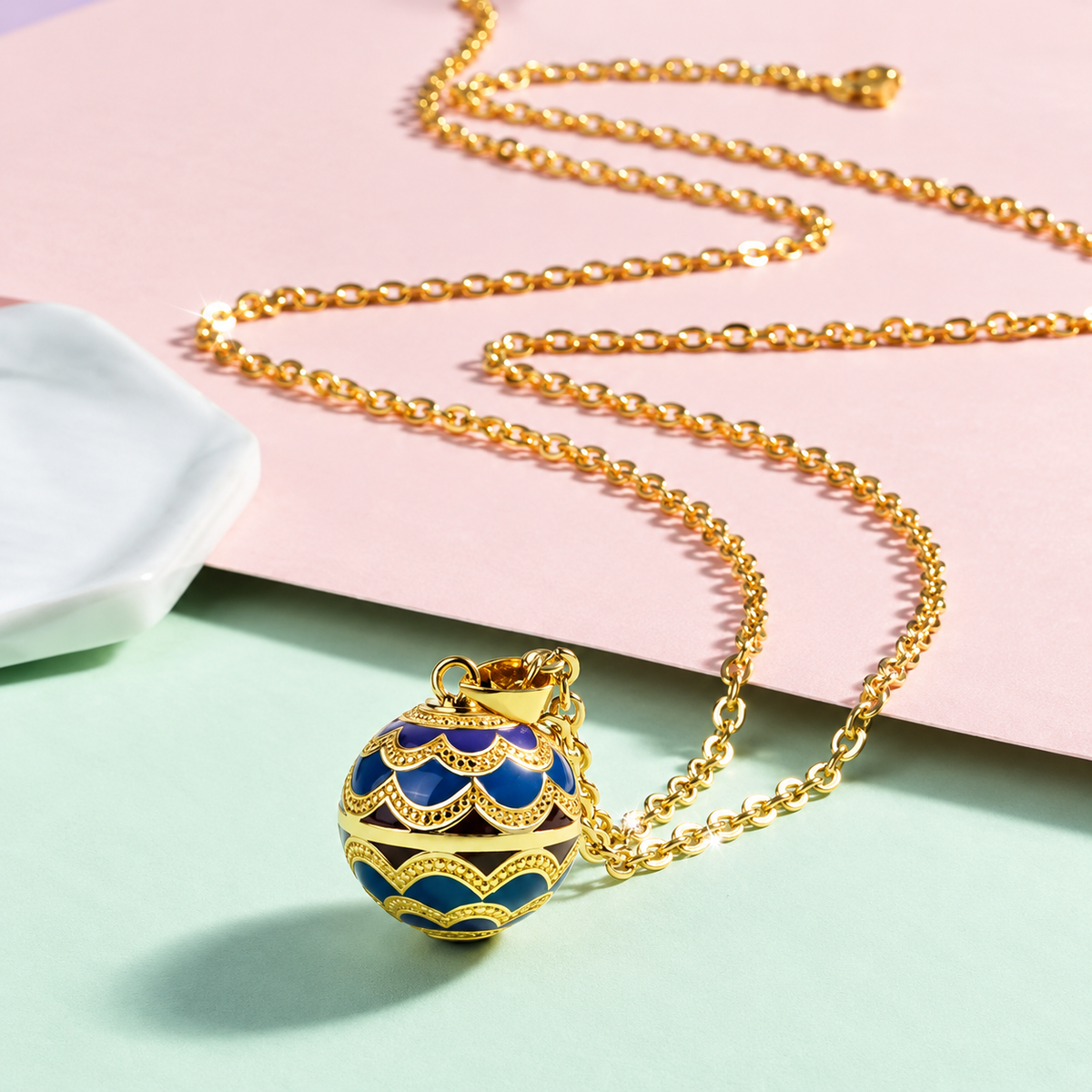 Collier bola Avelia posé sur fond rose et vert d’eau