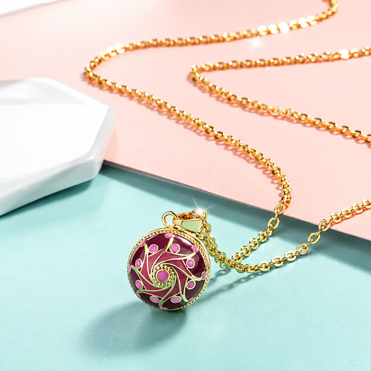 Collier bola Ayla posé sur fond rose et vert d’eau