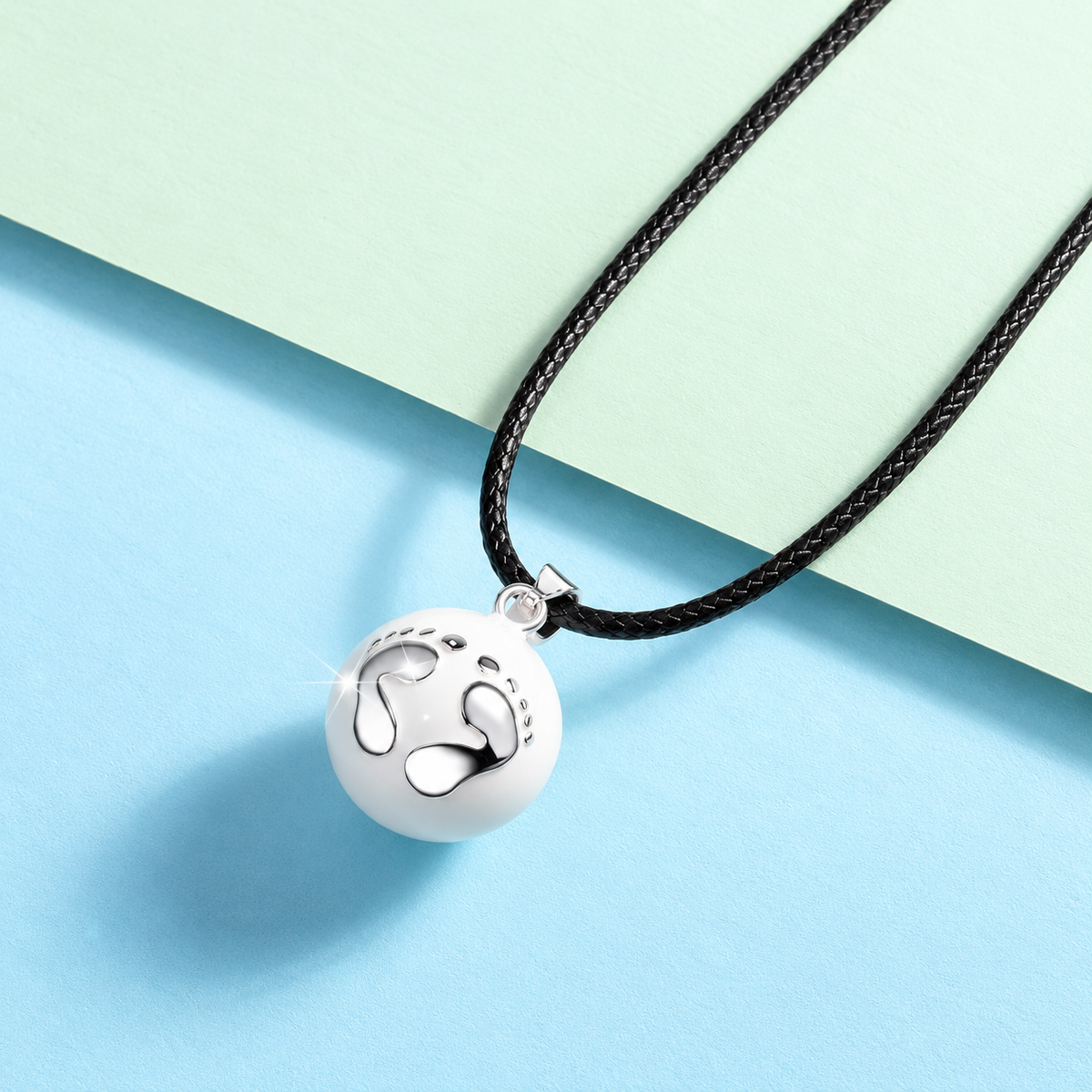 Pendentif bola Éclosion et son cordon noir sur fond pastel