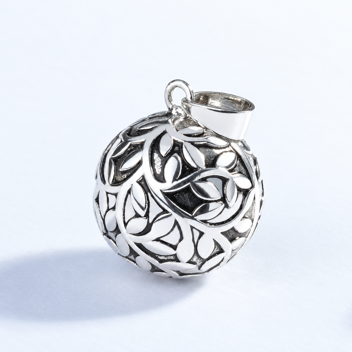 Pendentif bola Eliora argenté vu de trois quarts, feuillage ajouré