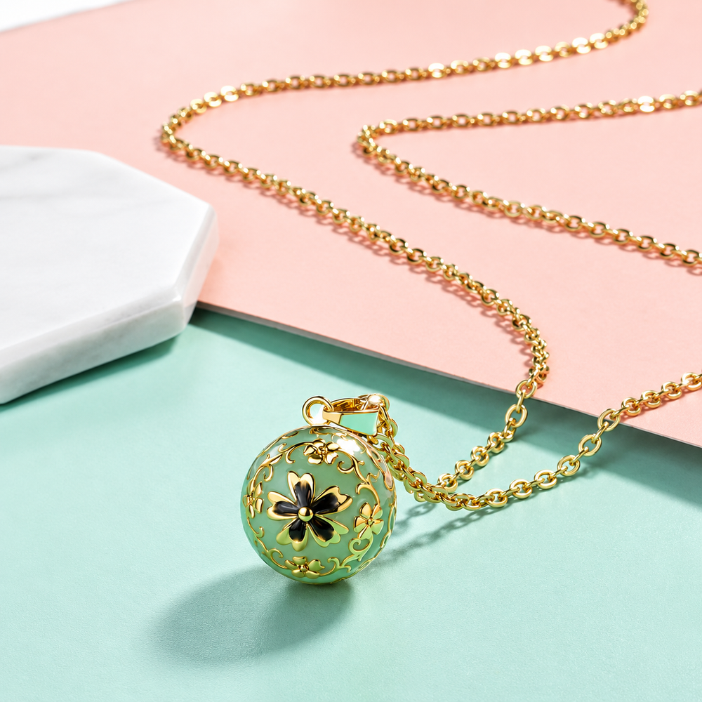Collier bola Élise posé sur fond rose et vert d’eau