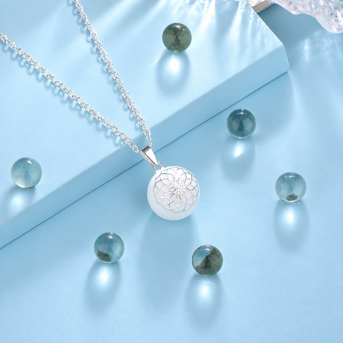 Bola Élune et sa chaîne argentée posés sur un support bleu clair