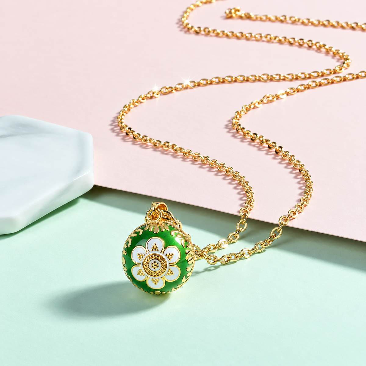 Collier bola Léana posé sur fond rose et vert d’eau