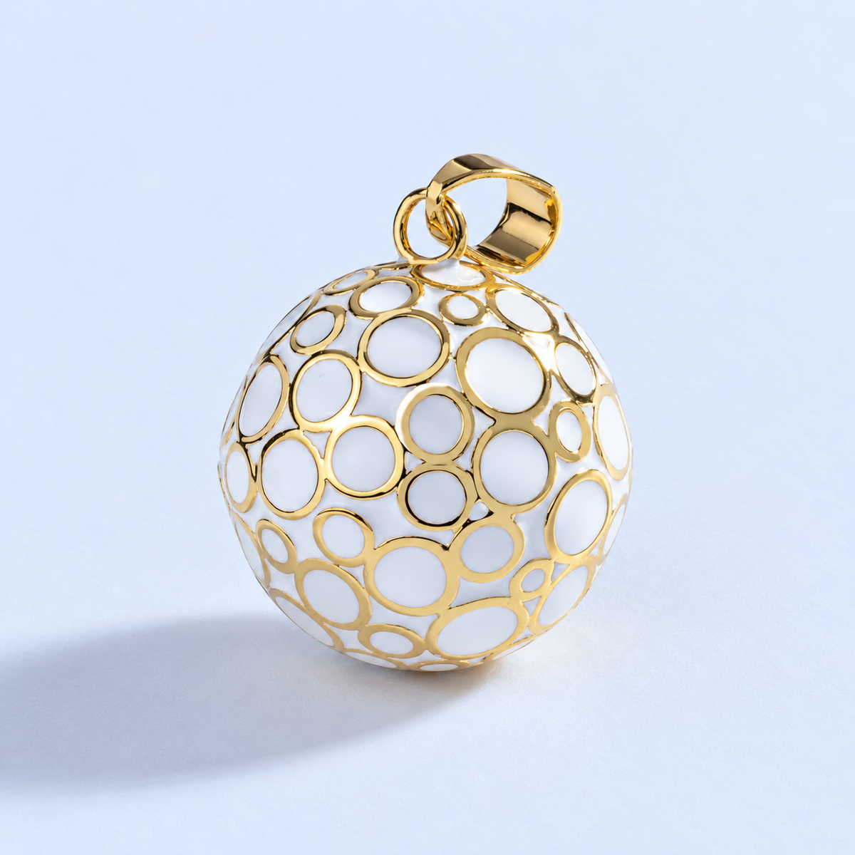 Pendentif bola Lunaé vu de trois quarts, anneaux dorés sur fond blanc