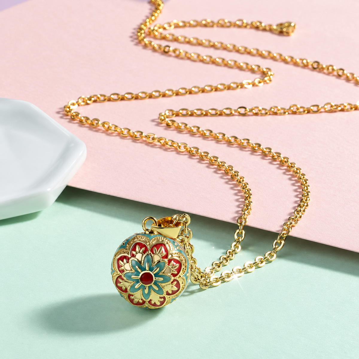 Collier bola Maïa posé sur fond rose et vert d’eau