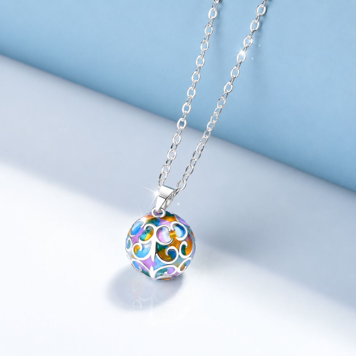 Collier bola Miraé coloré posé sur fond bleu clair