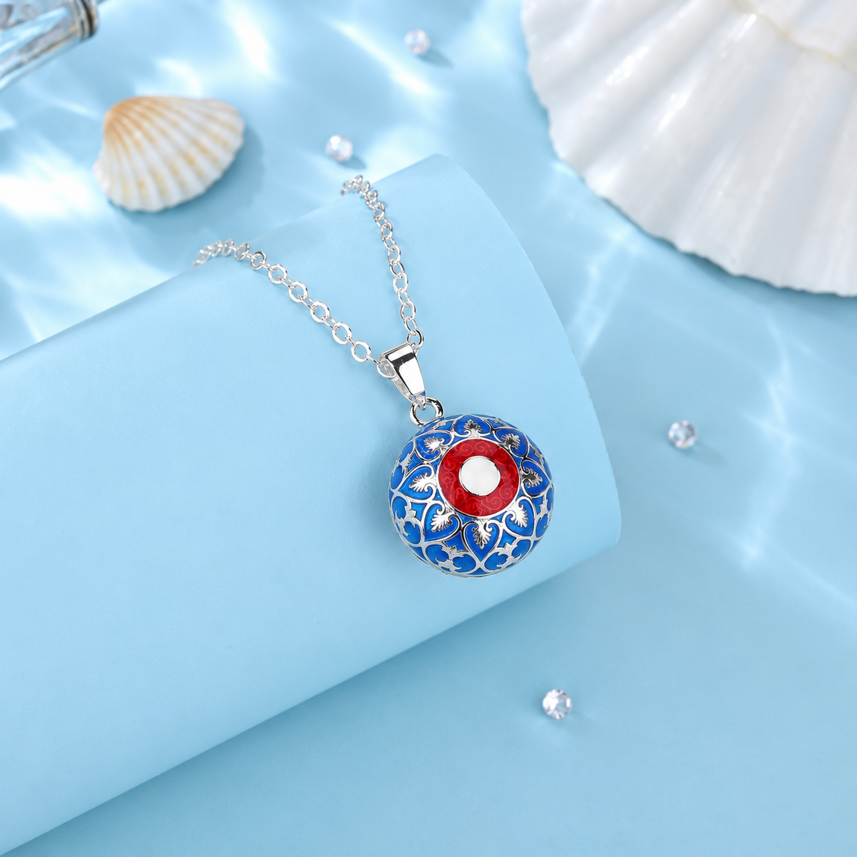 Collier bola Nahia posé sur un support bleu, coquillages en décor