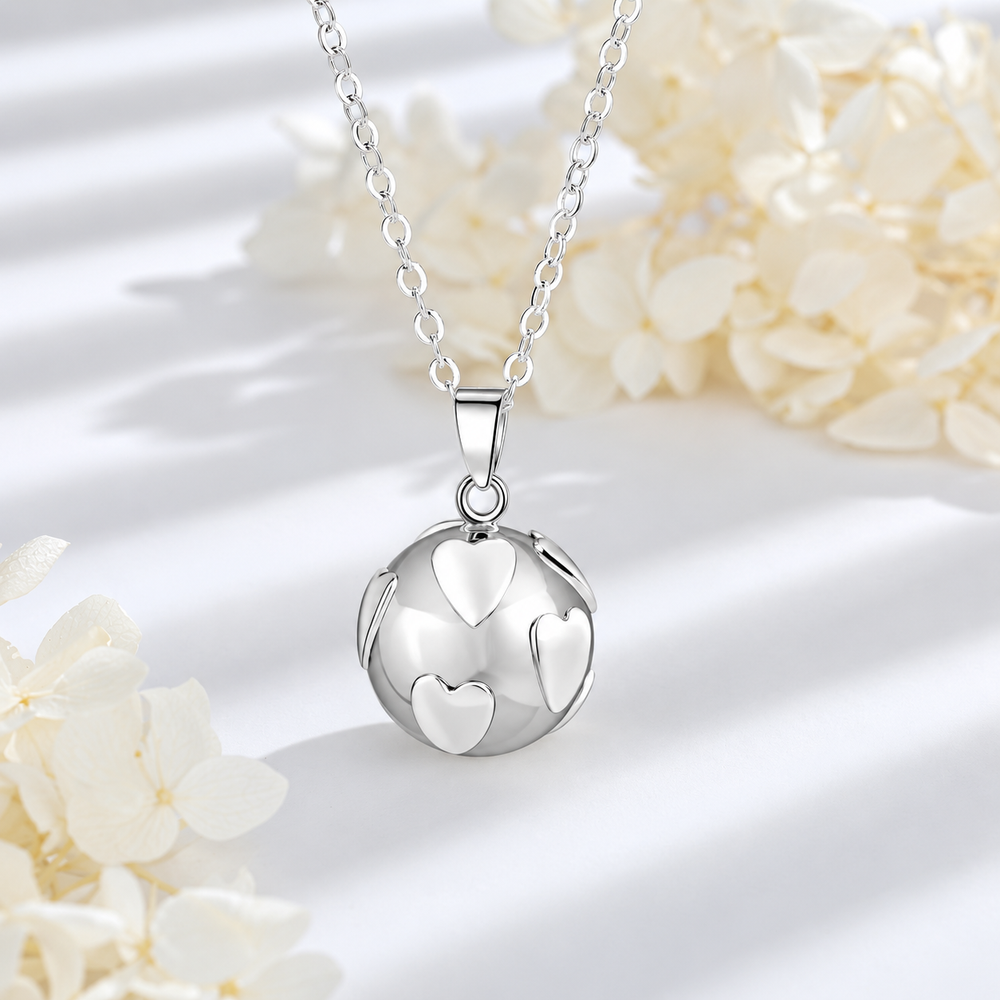 Collier bola Névéa posé sur fond blanc, fleurs claires en décor