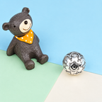 Pendentif bola Noa vu de dessous à côté d’une figurine d’ourson en décor