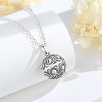 Collier bola Noa posé sur un support blanc, fleurs claires en décor
