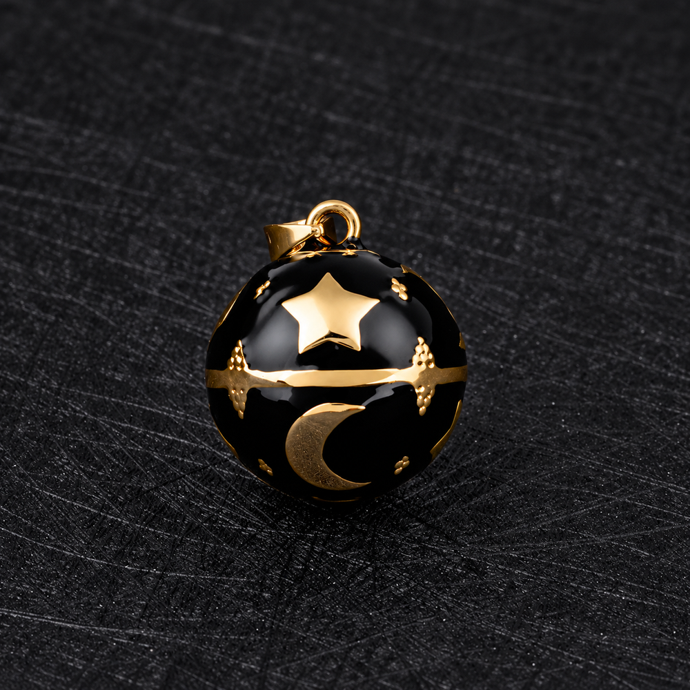 Pendentif bola Noctéa noir et doré posé sur un tissu noir
