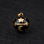 Pendentif bola Noctéa noir et doré posé sur un tissu noir