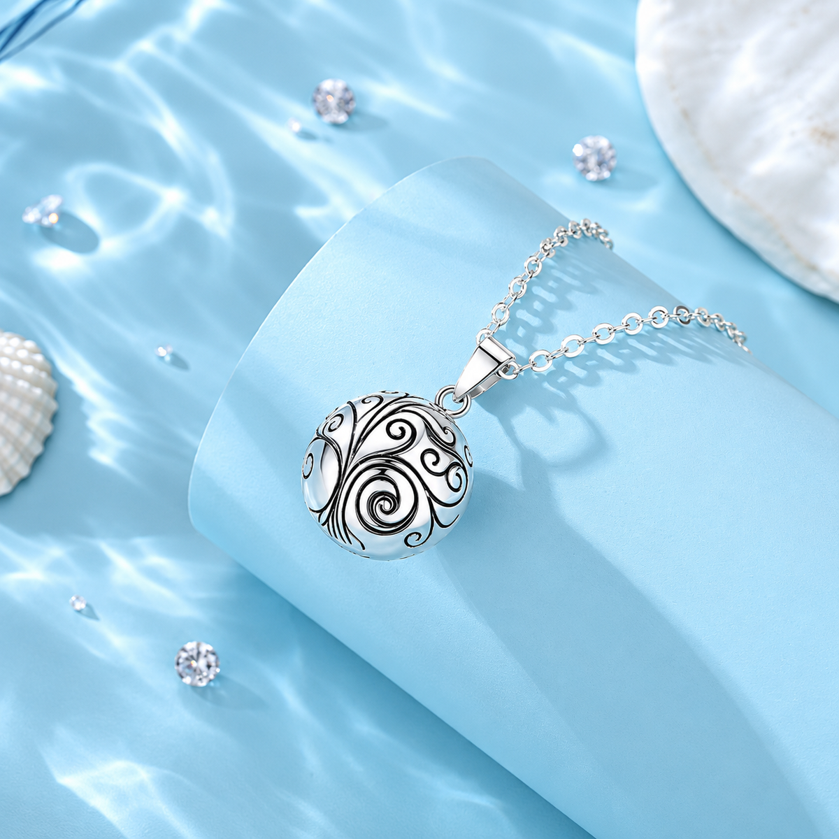Collier bola Oria posé sur un support bleu, coquillages en décor