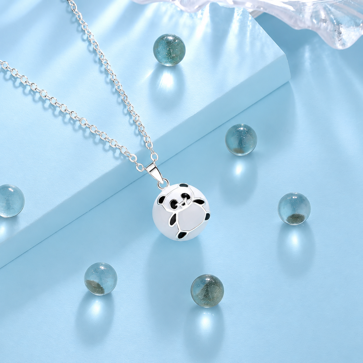 Collier bola Pandaï parmi des billes de verre, fond bleu