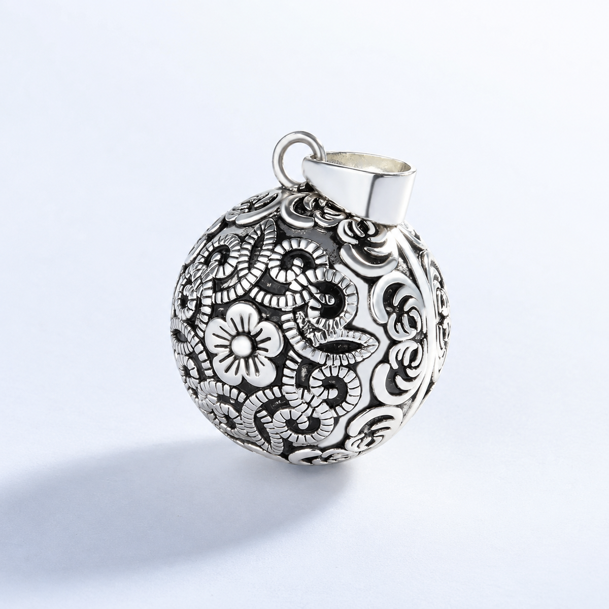 Pendentif bola Sélène vu de trois quarts, motif floral ajouré
