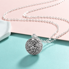 Collier bola Sélène posé sur fond rose et vert d’eau