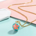 Collier bola Sohana posé sur fond rose et vert d’eau
