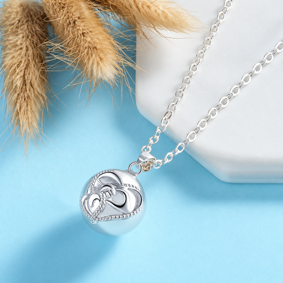 Collier bola Talia posé sur fond bleu, herbes séchées en décor